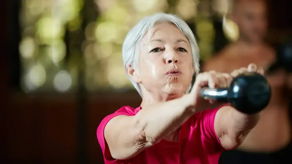 Older woman doing weight training Uckfield to help her strength and longevity 