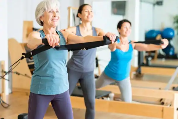 Toning Arms After 60: Empowering Womens Fitness Through Effective Weight Training 2 older woman doing weight training Uckfield and resistance in the gym to tone upper arms